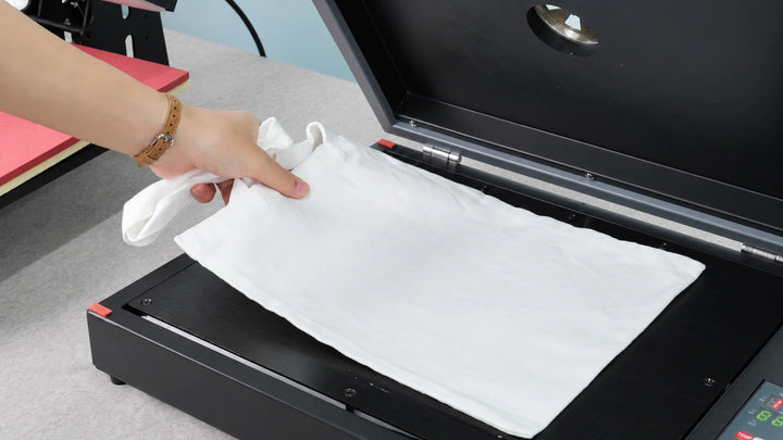 Placing a pretreated white T-shirt onto a heat press to dry and flatten the fabric before HeyGears G1X DTG printing.