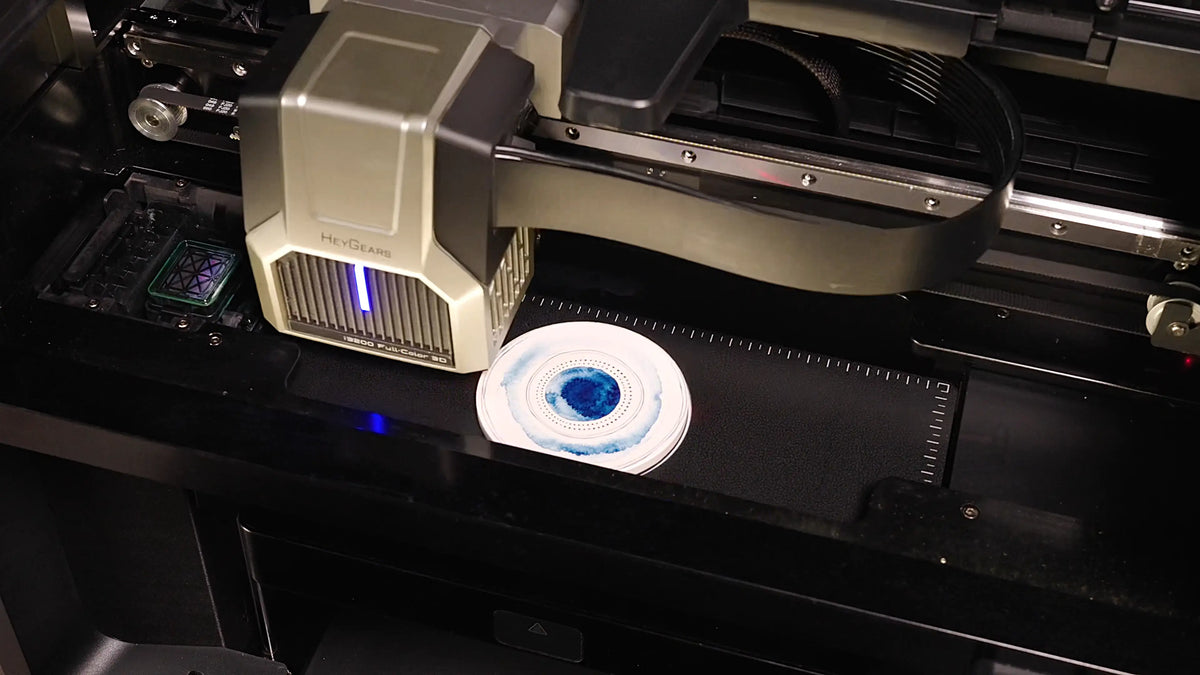 HeyGears G1X UV Edition printhead applying a blue circular design directly onto a white object using desktop UV printing.